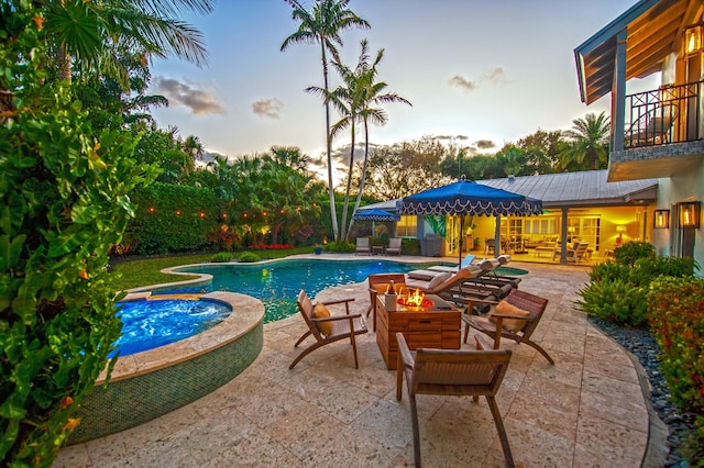 pool at dusk with an in ground hot tub, a patio, and an outdoor hangout area