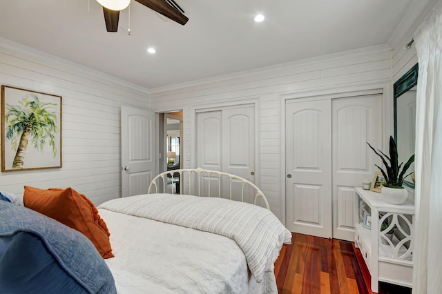 bedroom with ceiling fan, dark hardwood / wood-style flooring, crown molding, and two closets