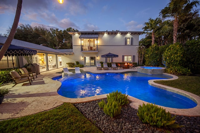 pool at dusk with a patio area and an in ground hot tub