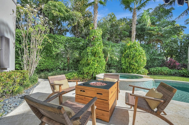 view of patio / terrace with a swimming pool with hot tub and an outdoor fire pit