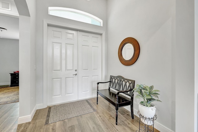 entrance foyer with baseboards, visible vents, arched walkways, and wood finished floors