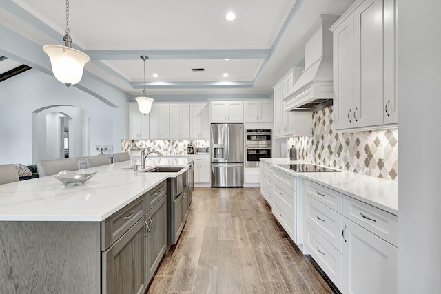 kitchen with premium range hood, a raised ceiling, white cabinetry, and stainless steel appliances