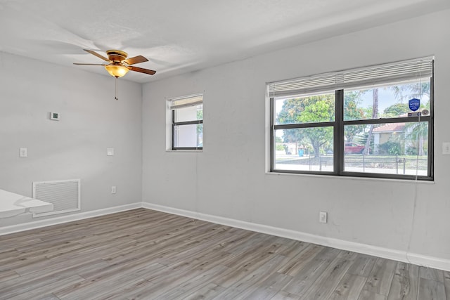 unfurnished room with light wood finished floors, baseboards, visible vents, and a ceiling fan