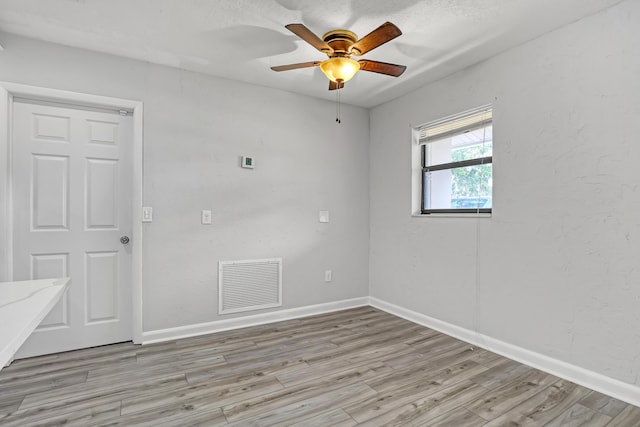 spare room with a ceiling fan, visible vents, light wood-style flooring, and baseboards