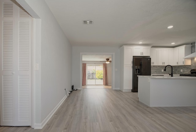 kitchen with tasteful backsplash, visible vents, black fridge with ice dispenser, white cabinetry, and light wood-type flooring