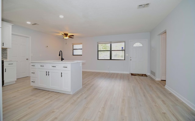 kitchen featuring light wood-style floors, light countertops, baseboards, and white cabinetry