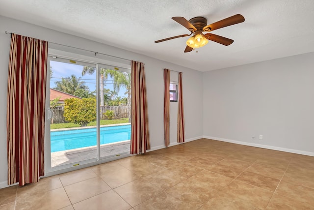 unfurnished room with a textured ceiling, ceiling fan, light tile patterned flooring, and baseboards