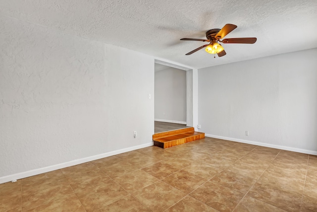 spare room with ceiling fan, a textured ceiling, and baseboards