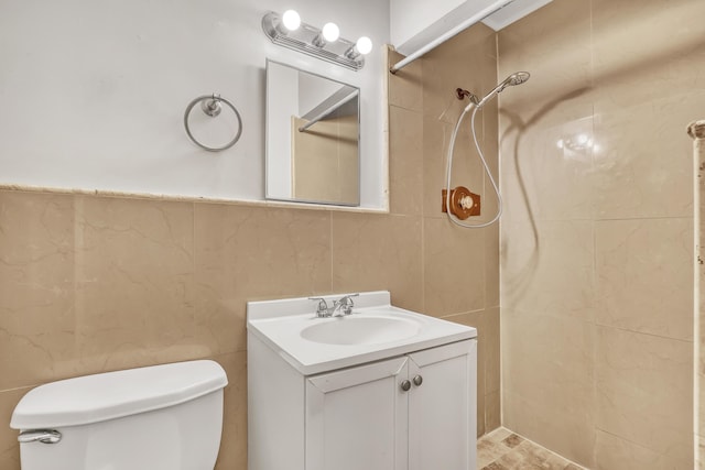 bathroom with tile walls, tiled shower, vanity, and toilet