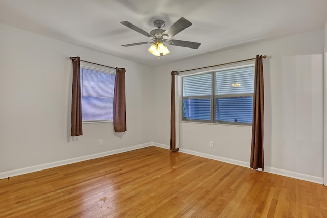 spare room with ceiling fan, light wood-style flooring, and baseboards