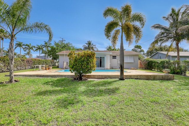 rear view of property featuring a fenced in pool, a lawn, fence, and stucco siding