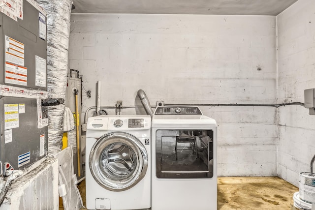 clothes washing area featuring concrete block wall, laundry area, and separate washer and dryer