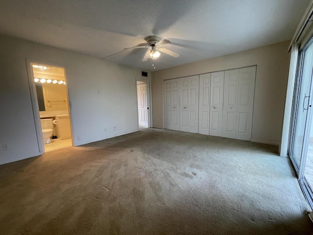 unfurnished bedroom featuring ensuite bath, ceiling fan, light carpet, a textured ceiling, and a closet