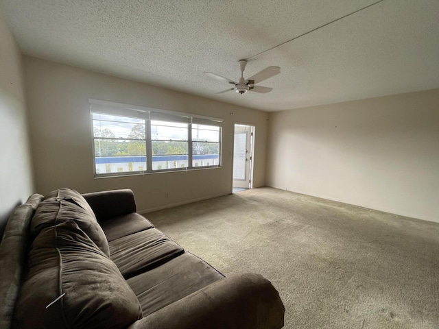 living room featuring ceiling fan, light carpet, and a textured ceiling