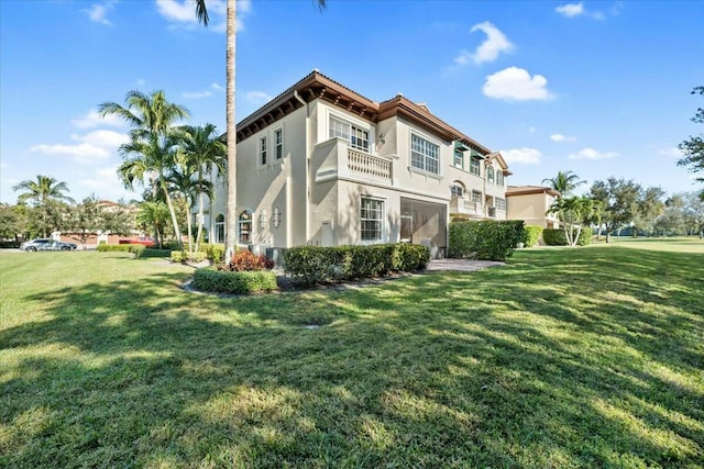 rear view of house with a lawn and a balcony