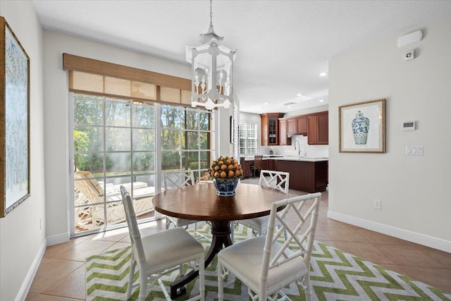 tiled dining space featuring a notable chandelier, sink, and a wealth of natural light