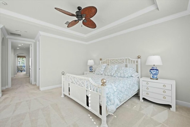 bedroom featuring ceiling fan, light colored carpet, ornamental molding, and a tray ceiling