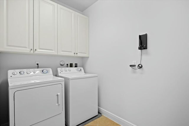 laundry area featuring cabinets, light tile patterned floors, and washing machine and clothes dryer