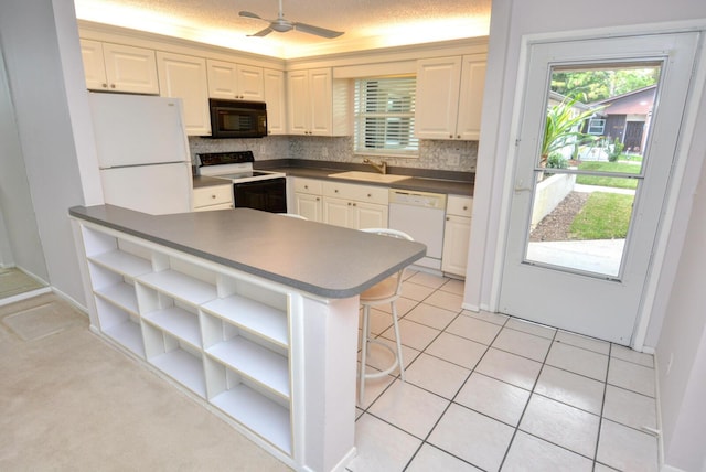 kitchen with sink, kitchen peninsula, a textured ceiling, white appliances, and a breakfast bar area