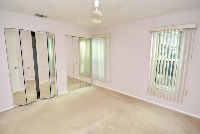 unfurnished bedroom with two closets and light colored carpet