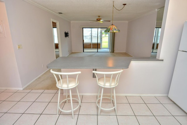 kitchen with ceiling fan, kitchen peninsula, a textured ceiling, a kitchen bar, and ornamental molding