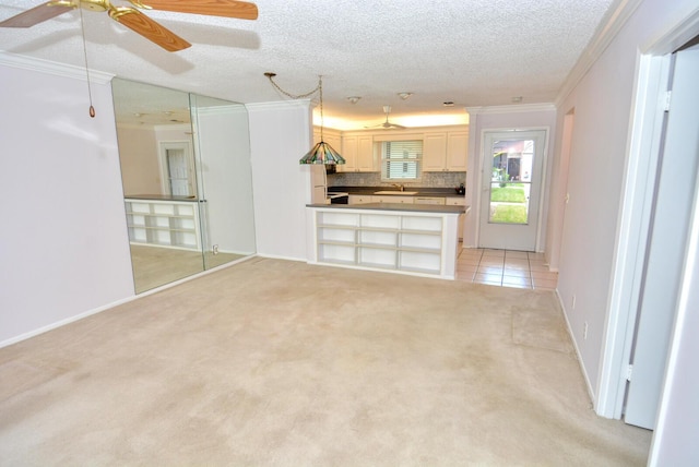 unfurnished living room featuring light carpet, a textured ceiling, ornamental molding, and sink