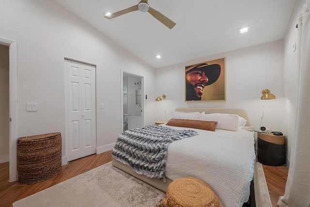 bedroom featuring light hardwood / wood-style flooring, vaulted ceiling, ceiling fan, connected bathroom, and a closet