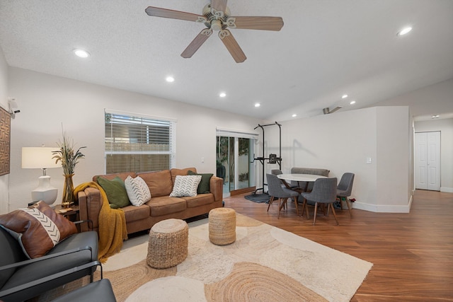 living room featuring lofted ceiling, ceiling fan, wood-type flooring, and a textured ceiling