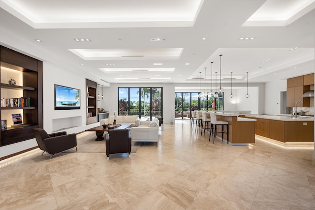 living room featuring sink, built in features, and a tray ceiling