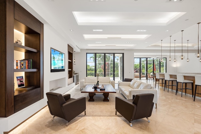 living room featuring a healthy amount of sunlight, a raised ceiling, and built in shelves