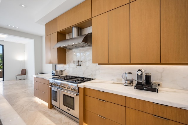 kitchen featuring range with two ovens, wall chimney range hood, decorative backsplash, and light stone countertops