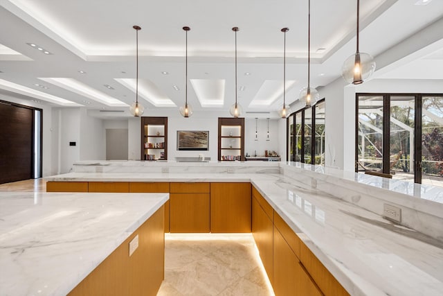 kitchen featuring hanging light fixtures, light stone counters, and a tray ceiling