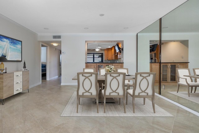 tiled dining space featuring crown molding and ceiling fan