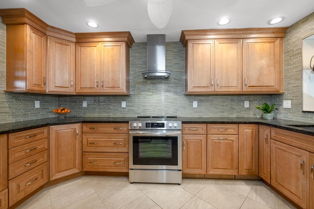 kitchen with decorative backsplash, dark stone counters, wall chimney exhaust hood, light tile patterned floors, and stainless steel electric range oven