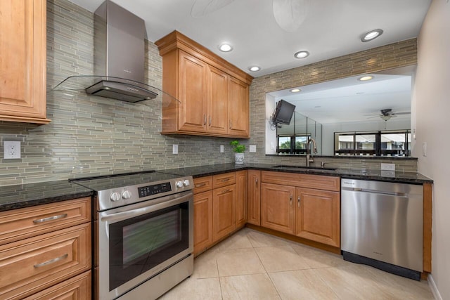 kitchen featuring decorative backsplash, appliances with stainless steel finishes, wall chimney exhaust hood, ceiling fan, and sink