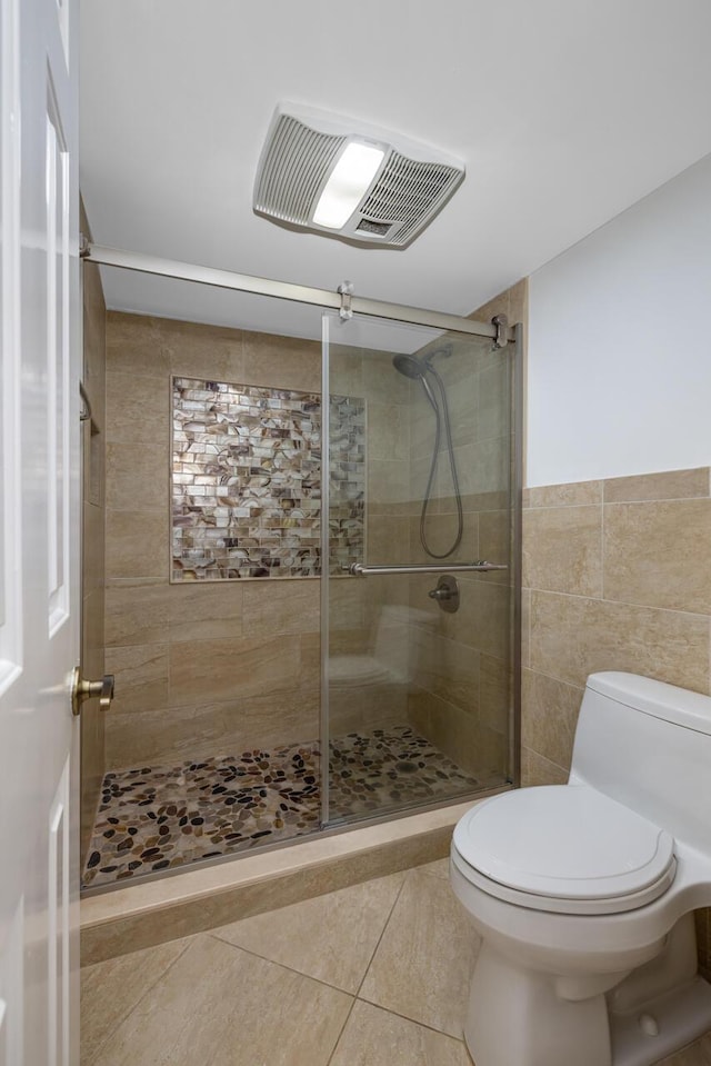 bathroom featuring walk in shower, tile patterned flooring, tile walls, and toilet