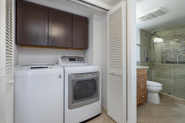 clothes washing area featuring cabinets, light tile patterned floors, and washer and dryer