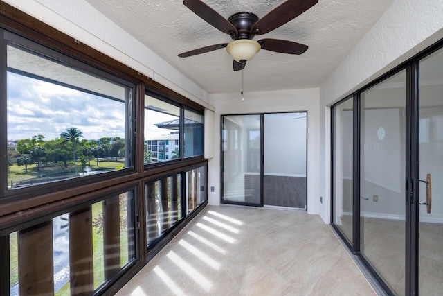 unfurnished sunroom featuring ceiling fan