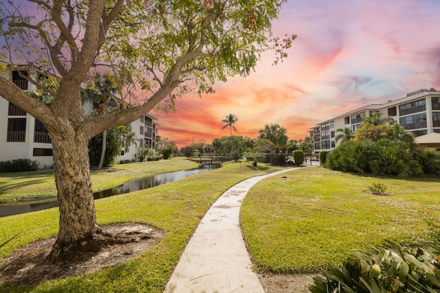 view of property's community with a lawn and a water view