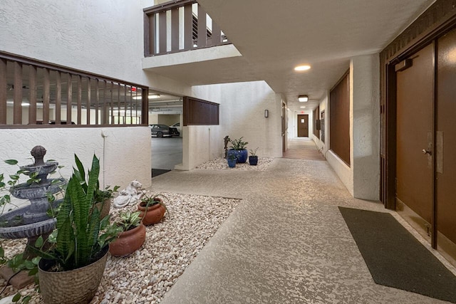 corridor featuring light colored carpet and a textured ceiling