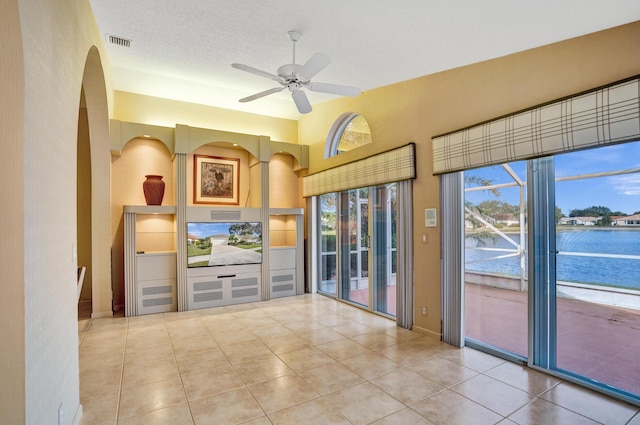 unfurnished living room featuring light tile patterned flooring, a textured ceiling, and ceiling fan