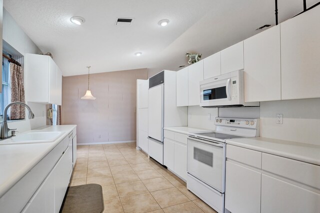 kitchen featuring white appliances, sink, light tile patterned floors, and white cabinetry