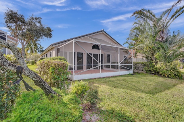 rear view of house with a lanai and a lawn