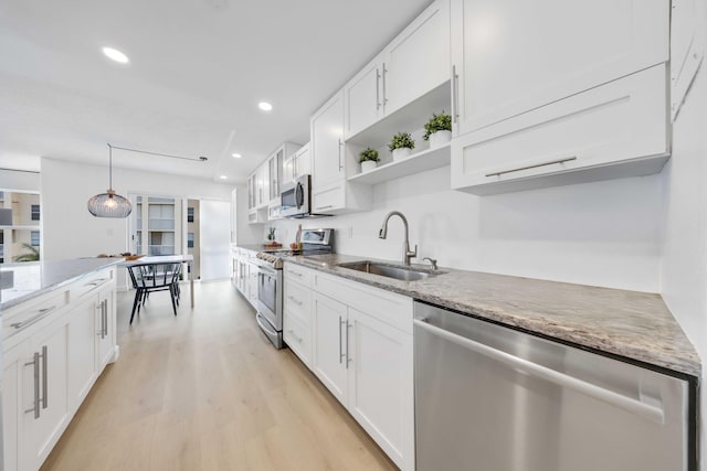 kitchen with pendant lighting, sink, light hardwood / wood-style flooring, white cabinetry, and stainless steel appliances