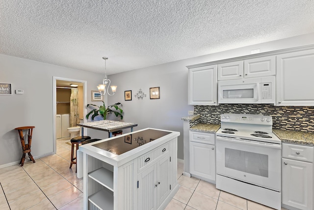 kitchen featuring washer and dryer, white cabinetry, white appliances, and decorative light fixtures