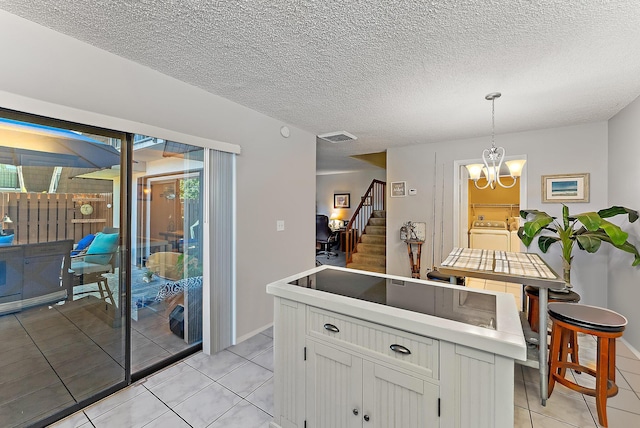 kitchen with an inviting chandelier, washing machine and dryer, a textured ceiling, decorative light fixtures, and light tile patterned flooring