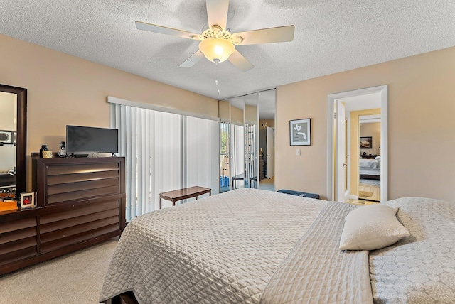 bedroom featuring ceiling fan, light colored carpet, a textured ceiling, and a closet