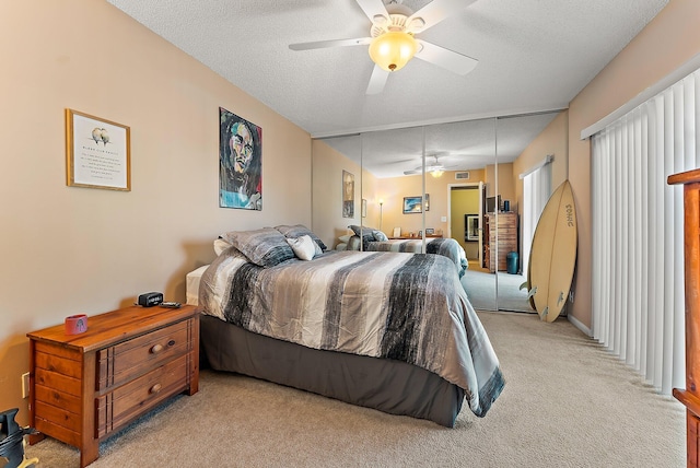 bedroom with a textured ceiling, light colored carpet, a closet, and ceiling fan