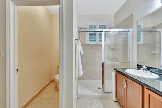 bathroom with tile patterned flooring, vanity, toilet, and walk in shower