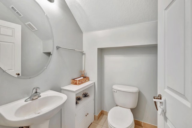 bathroom with tile patterned flooring, toilet, sink, and a textured ceiling